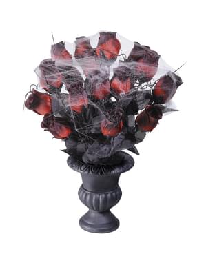 Blomstervase med røde roser og spindelvæv